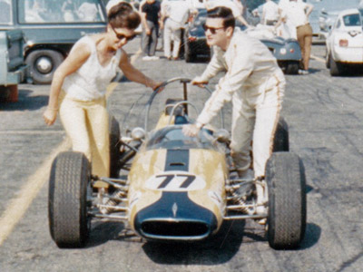 Owner Eva H Kirk and driver Allen Treuhaft push their Brabham BT10 through a race paddock in 1967. Copyright Frederick Amey 2020. Used with permission.
