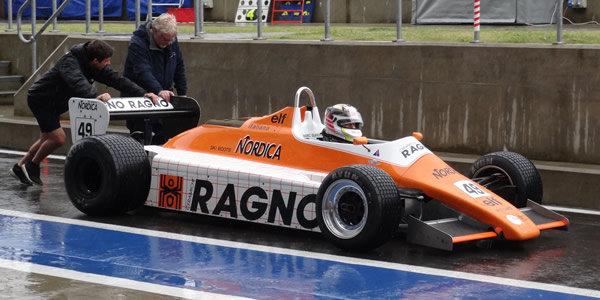Historic motor racing is pure glamour.  Neil Glover is pushed down the Wing pit road after practice for the 2015 Silverstone Classic in his A5-specification Arrows. Copyright Keith Lewcock 2015. Used with permission.