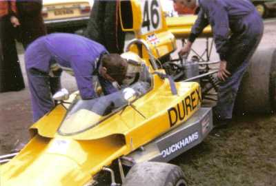 Richard Scott is fitted into John Turner's Lola T330 HU18 at Mallory Park in 1975. Copyright Simon Lewis 2004. Used with permission.