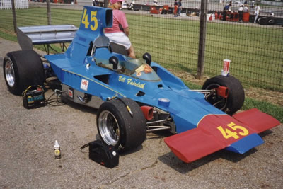 Bill Faircloth's Lola T332 at Mid-Ohio in 1996 or 1997.  Note the holes in the scoop bodywork near the roll hoop and near the h in Faircloth for the roll cage that Thomas used. Copyright Bill Peters 2001. Used with permission.