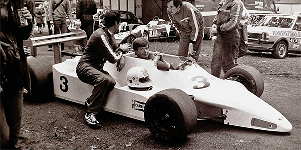 Gary Gibson in the Chevron B56 at Phoenix Park in 1982 as his crew Terry Wilkinson (on sidepod) and Davey Connolly exchange views. Copyright Ian Lynas 2022. Used with permission.