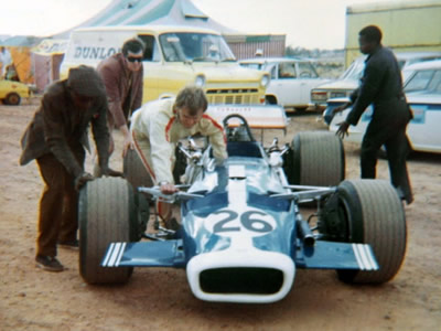 John Amm's T140 is pushed through the paddock.  Note the 1970-spec low wings and nose wings, quite unlike the red #25 Domingo T140 shown elsewhere on this page. Copyright Doug Brown 2005. Used with permission.