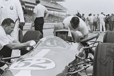 Jack Brabham awaits while the Zinc crew tend to the Brabham BT12 at Indy in 1964.  Part of the Dave Friedman collection. Licenced by The Henry Ford under Creative Commons licence Attribution-NonCommercial-NoDerivs 2.0 Generic. Original image has been cropped.