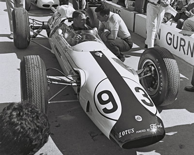 Dan Gurney in the #93 Lotus 29 confers with teammate Jim Clark before the start of the 1963 Indianapolis 500.  Part of the Dave Friedman collection. Licenced by The Henry Ford under Creative Commons licence Attribution-NonCommercial-NoDerivs 2.0 Generic. Original image has been cropped.
