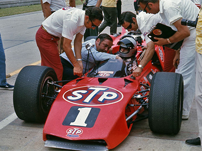 Andy Granatelli confers with Mario Andretti in the new STP McNamara 500 at the 1970 Indy 500.  Copyright Indianapolis Motor Speedway. Copyright permissions granted for non-commercial use by Indianapolis Motor Speedway.