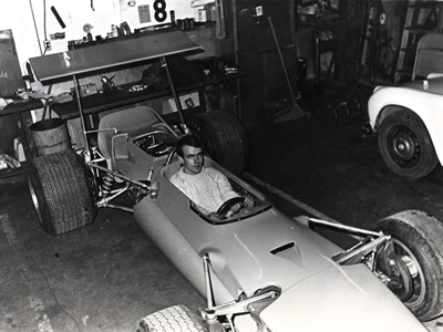 Mike Kramer tries Ron Courtney's Lola for size while it was being completed at Carrera Motors in Lombard,  Illinois.  The model of Courtney's Lola wasn't published but the photo shows a standard T142. Copyright Mike Kramer 2008. Used with permission.