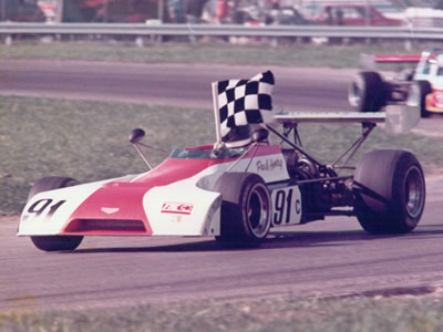 Paul Henry celebrating his first Formula C win in the Chevron B25, at IRP in 1974.  Note it still has a B25 nose. Copyright Paul Henry 2009. Used with permission.