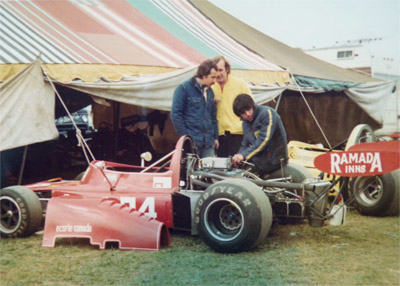 Joe Grimaldi sitting on the rear wheel of Dale Lang's Ramada Inns-liveried March 74B at Watkins Glen in October 1974. Copyright Eddie Villa 2019. Used with permission.